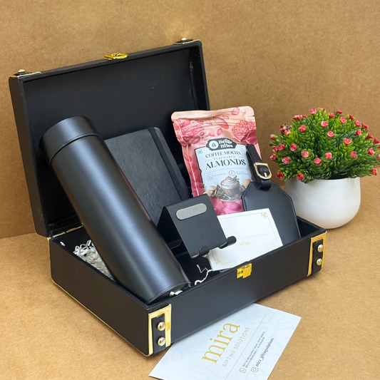 Black briefcase with a thermos, snacks, and a watch on a brown surface.