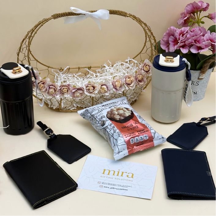 Collection of items including a basket, water bottle, snacks, and wallets on a light surface with flowers in the background.