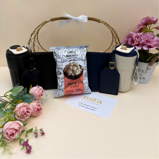 Product display with black bags, a bag of snacks, a water bottle, and flowers on a light surface.