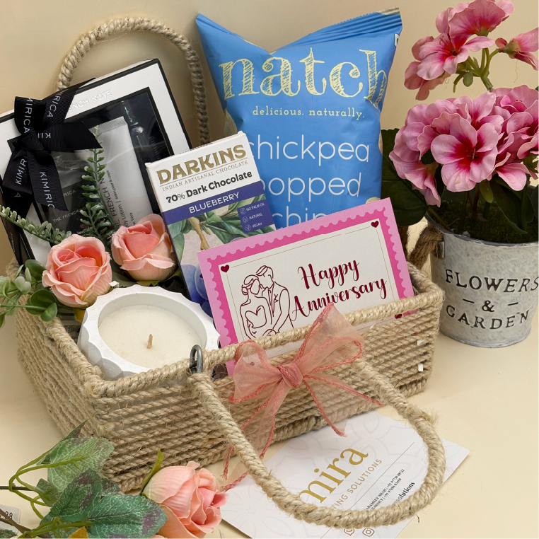 Gift basket with candles, snacks, and flowers on a table