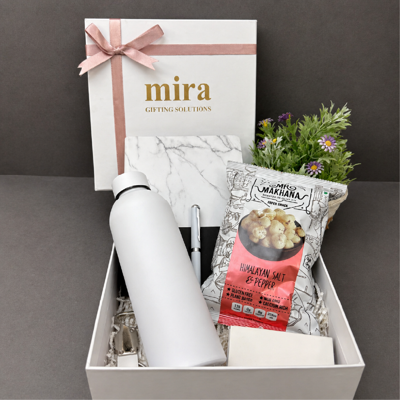 Gift box with a white water bottle, snacks, and a plant on a dark surface.