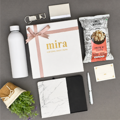 Collection of items including a book titled 'mira', a water bottle, a plant, and other small objects on a gray surface.