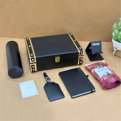 Collection of black leather items including a box, notebook, tag, and pen holder on a beige surface.