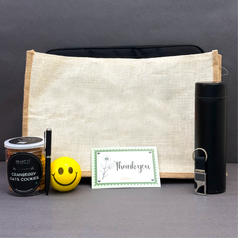 Gift set with a bag, cookies, a smiley face ball, and a card on a gray background
