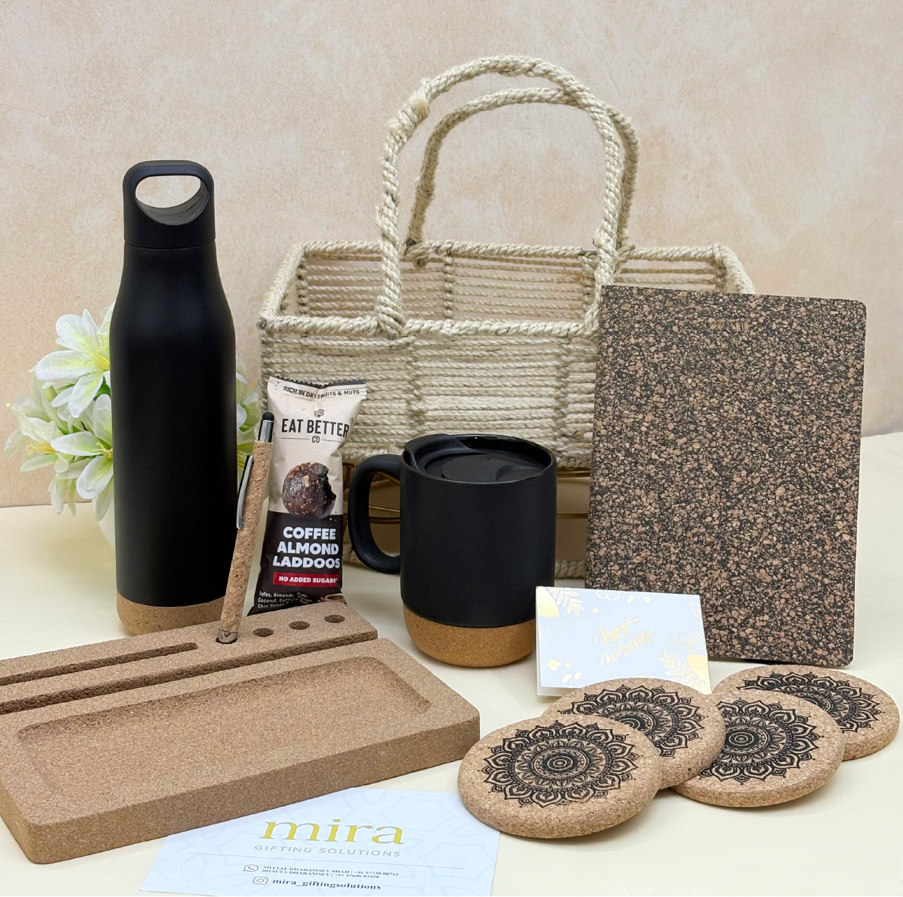 Collection of eco-friendly products including a black water bottle, mug, and coasters on a light surface.