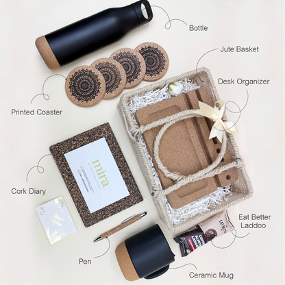 Collection of eco-friendly products including a bottle, jute basket, cork diary, printed coasters, ceramic mug, pen, and laddoo on a light background.