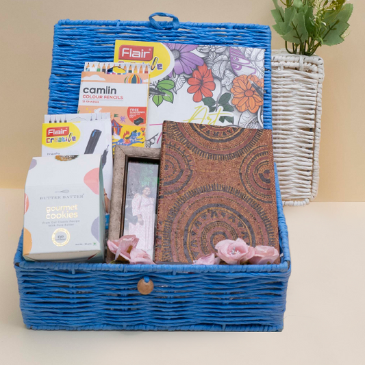 Blue wicker basket with stationery items including notebooks and colored pencils on a beige background.