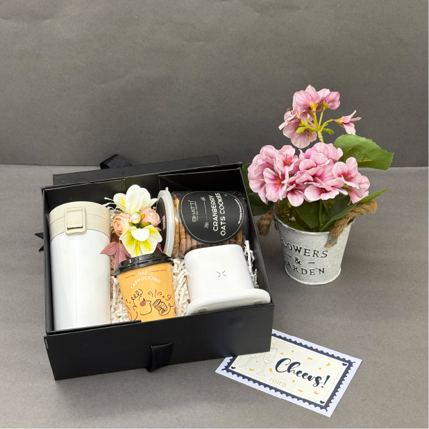 Gift set with coffee cups, thermos, and flowers on a gray surface