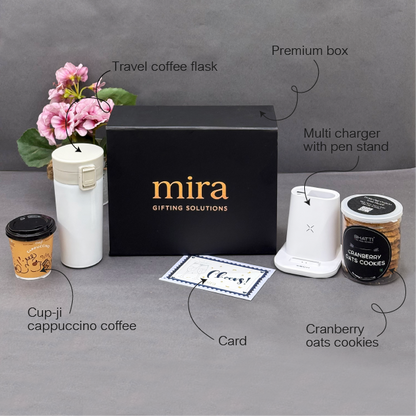 Gifting set with 'mira' branded box, travel coffee flask, multi charger, cup-jj coffee, card, and cranberry oats cookies on a gray surface.