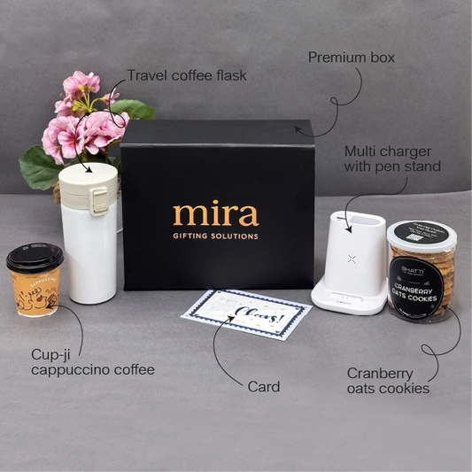 Gifting set with 'mira' branded box, travel coffee flask, multi charger, cup-jj coffee, card, and cranberry oats cookies on a gray surface.