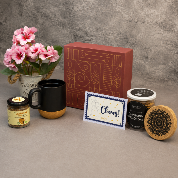 Gifting set with mug, candles, cookies, and card on a textured surface