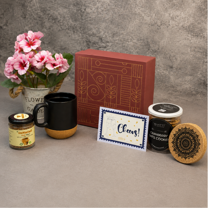 Gifting set with mug, candles, cookies, and card on a textured surface