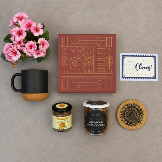 Mug, decorative box, jars, coaster, and card on a gray surface with pink flowers.