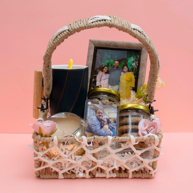 Wicker basket with jars, a mug, and a photo frame on a pink background