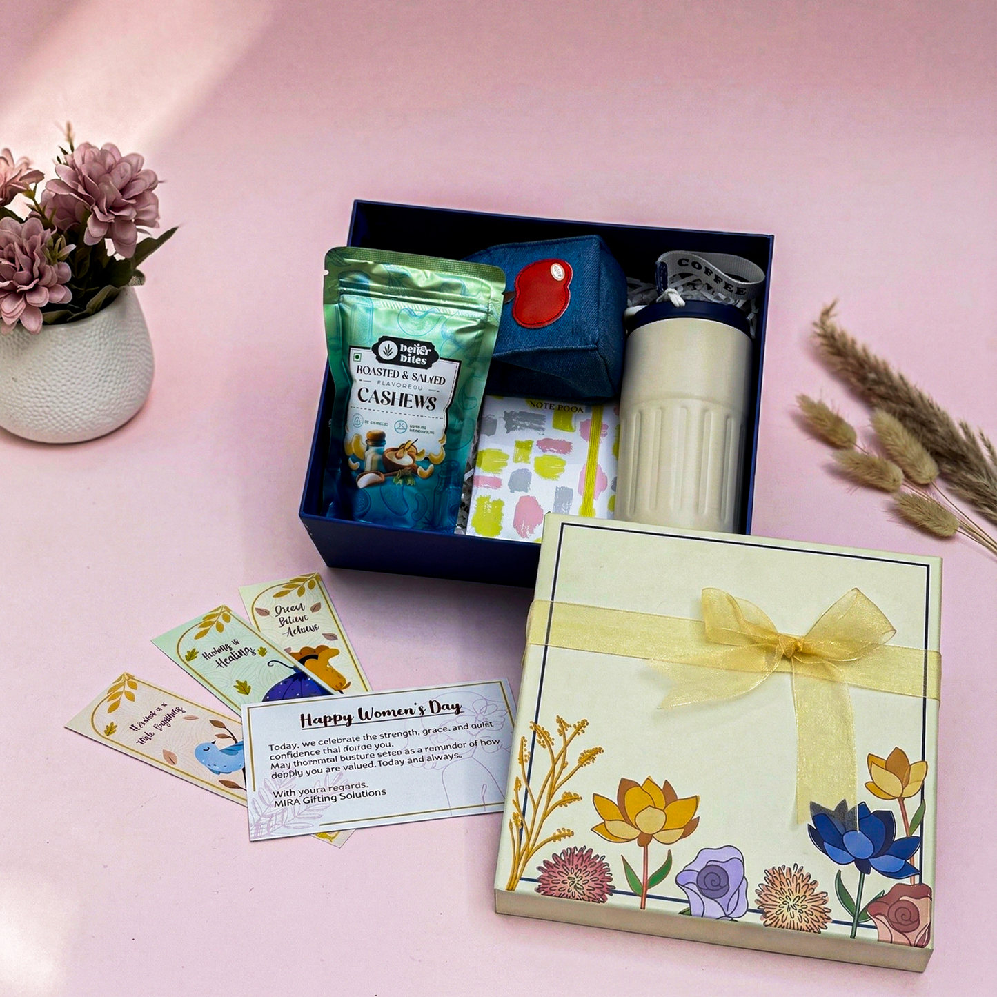 Gift set with cashews, a candle, and a card on a pink background
