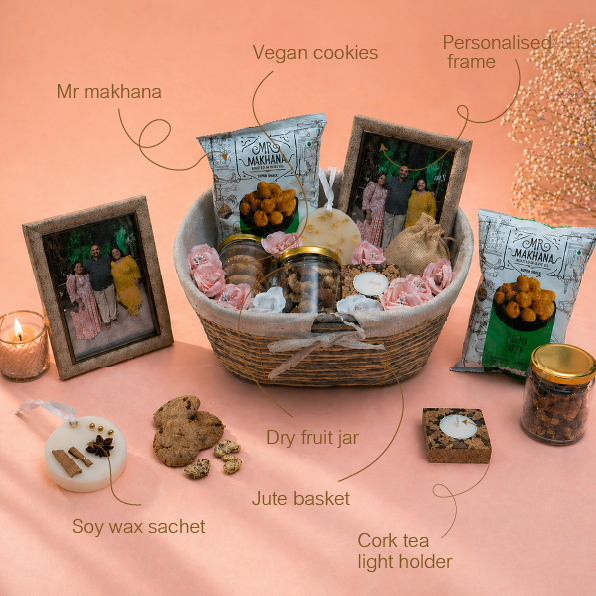 Gift basket with various items including cookies, a frame, and candles on a pink background
