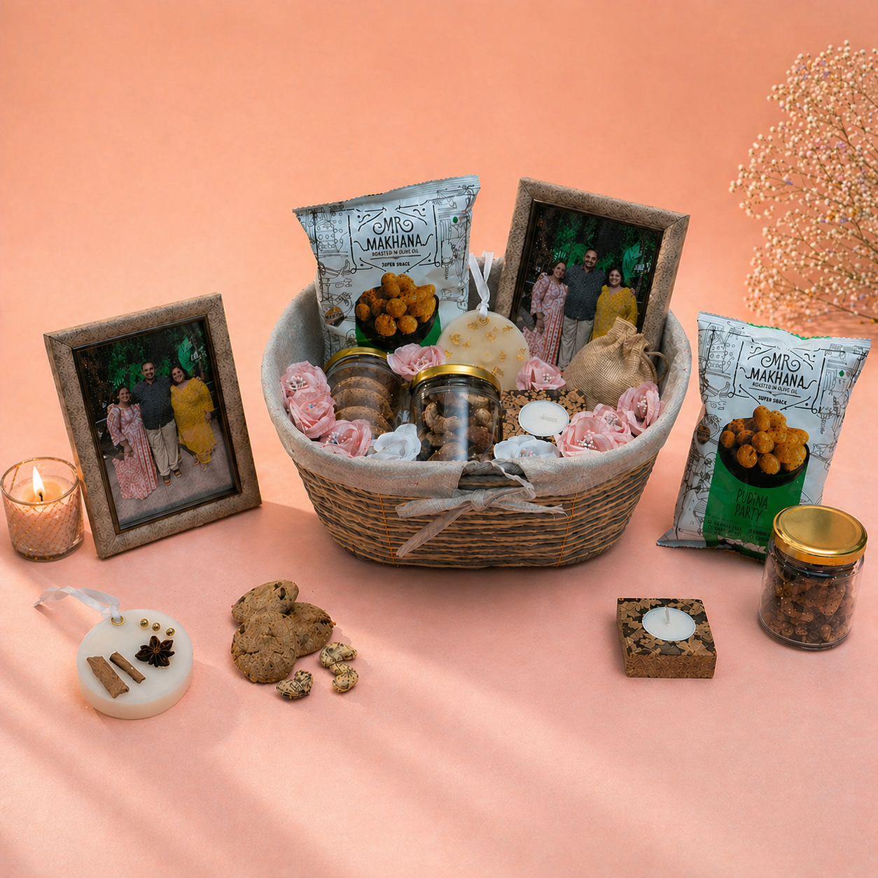 Gifting basket with snacks, candles, and decorative items on a peach background