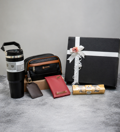Collection of travel and gift items including a tumbler, pouch, wallet, and wrapped gift on a gray surface.