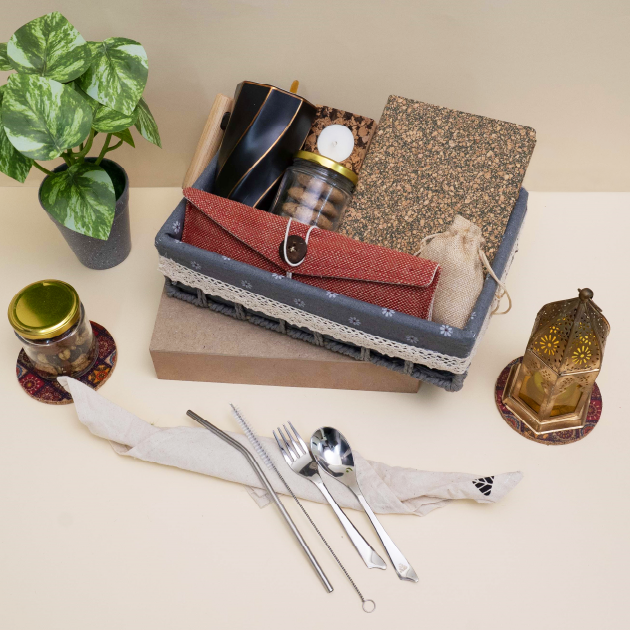 Set of cutlery and small items on a table with a plant and decorative objects.