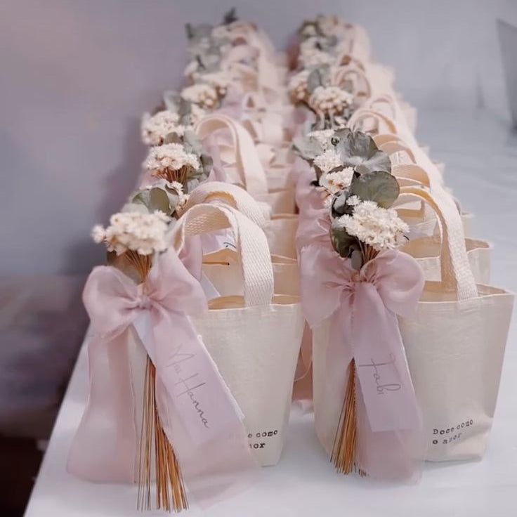 Decorative gift bags with flowers and ribbons on a white surface